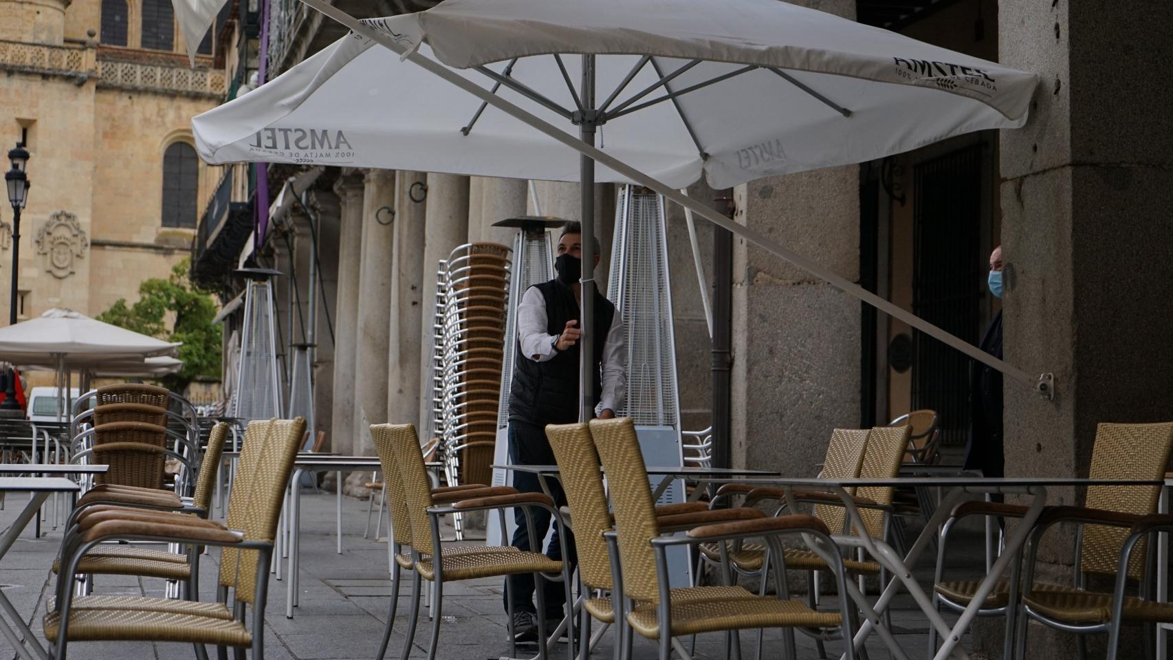 Un camarero atiende una terraza vacía.