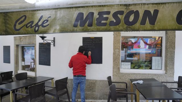 Un hombre escribe en la pizarra de un mesón, en Santiago de Compostela.