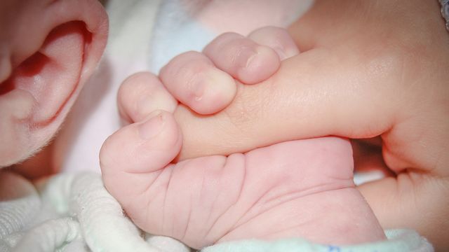 La mano de un adulto y la de un bebé.