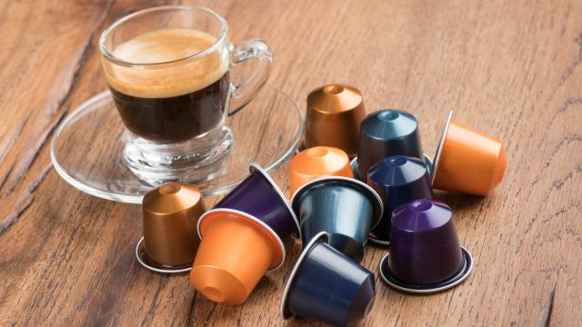 Unas cápsulas rodeando a un café recién hecho.