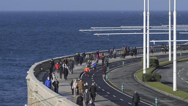 Varias personas caminan por el paseo marítimo en A Coruña.
