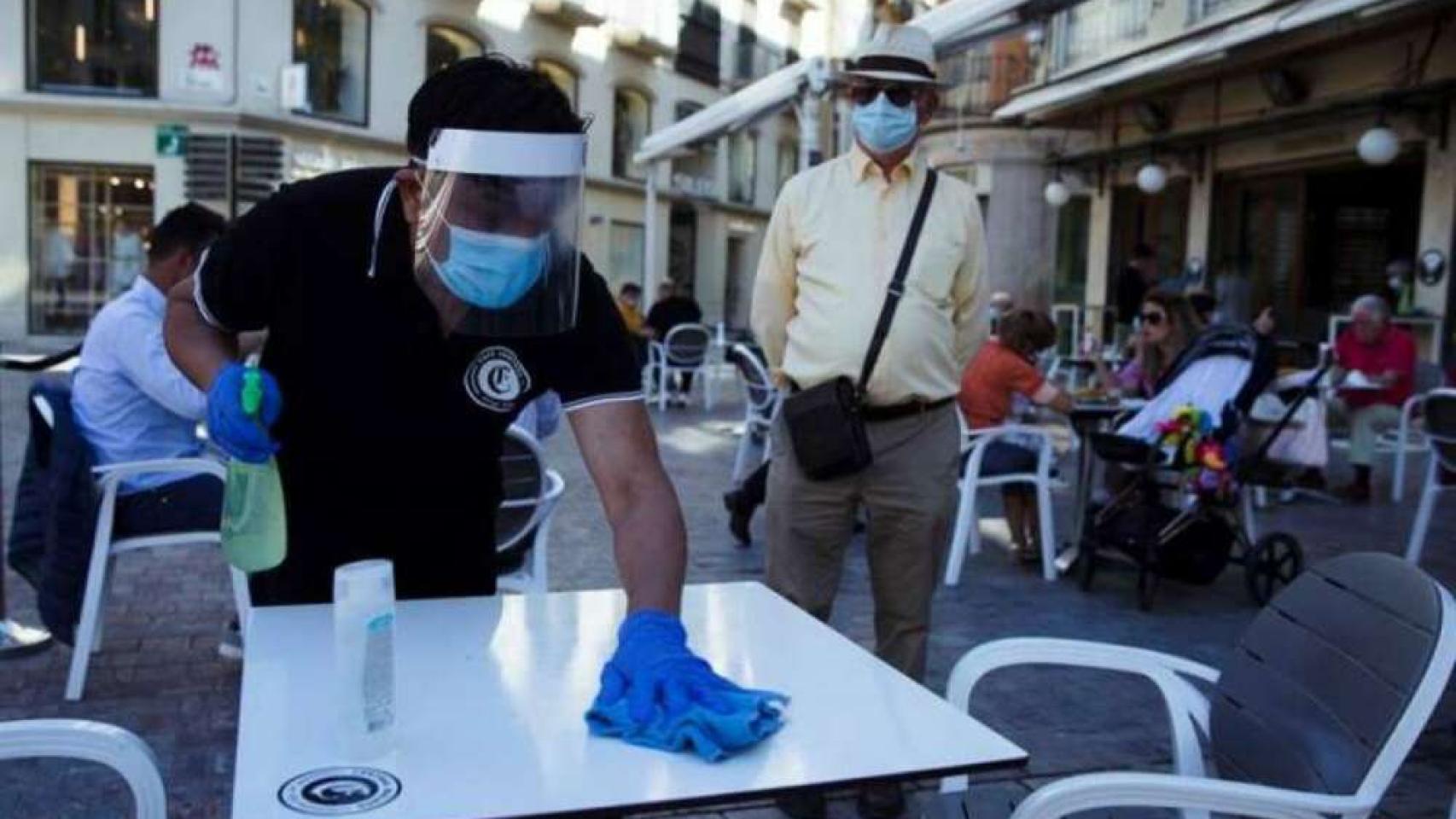 Un camarero limpia una mesa en una terraza, en imagen de archivo.