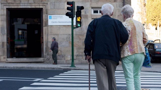 Una pareja de ancianos cruza una calle en Galicia