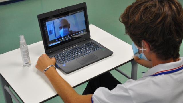 Un alumno en mitad de una clase con mascarilla.