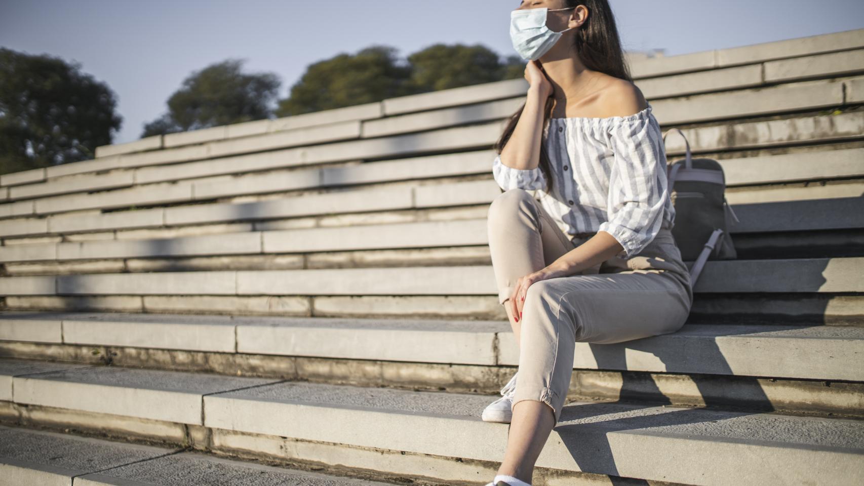 Una mujer toma el sol con mascarilla.