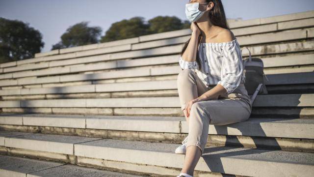 Una mujer toma el sol con mascarilla.