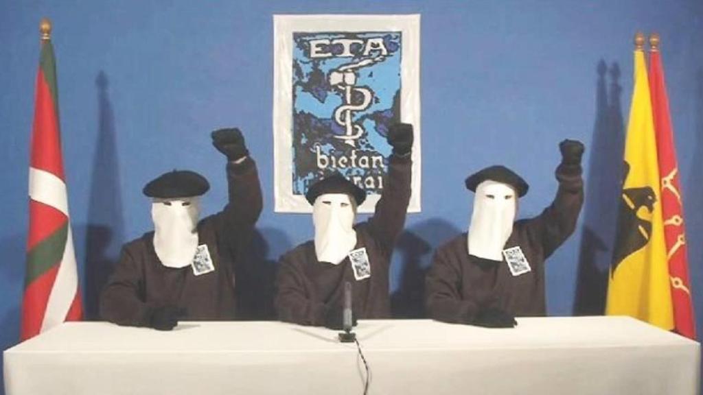 Tres miembros de ETA encapuchados alzan el puño.