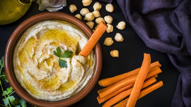 Un plato de barro con hummus y unos palitos de zanahoria.