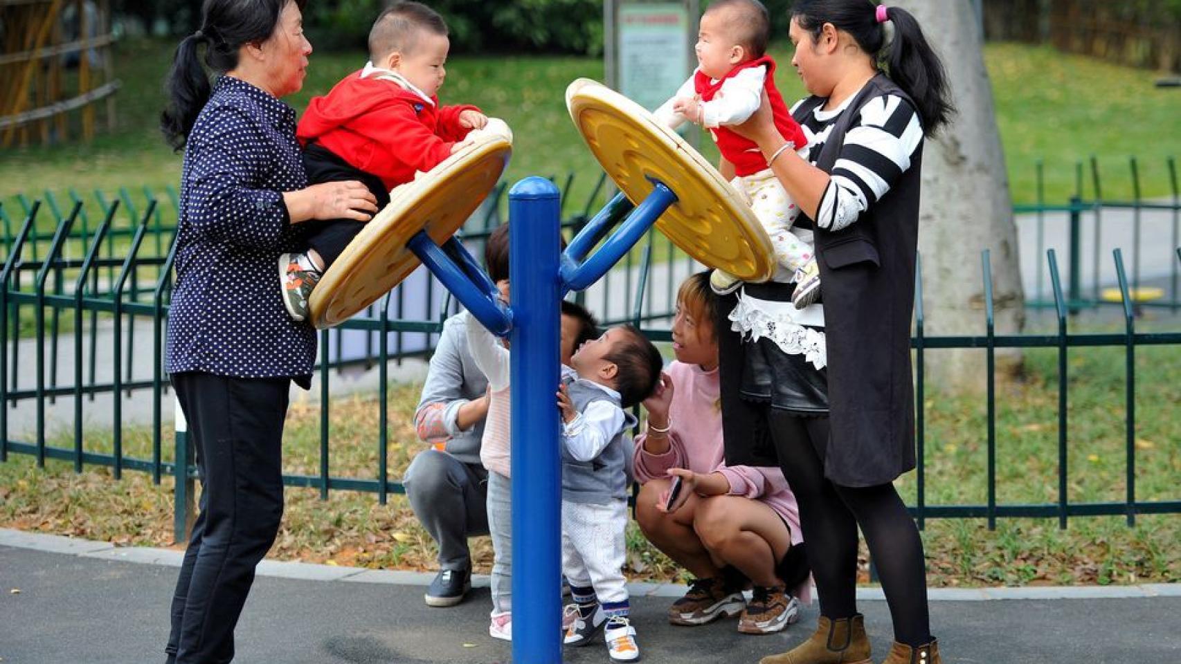 Tres mujeres juegan con varios niños pequeños en un parque.