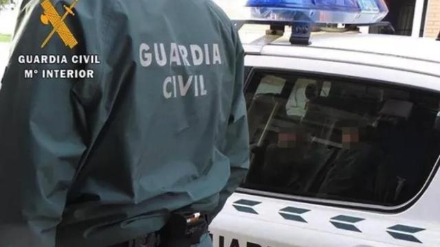 Un agente de la Guardia Civil junto a un coche patrulla.