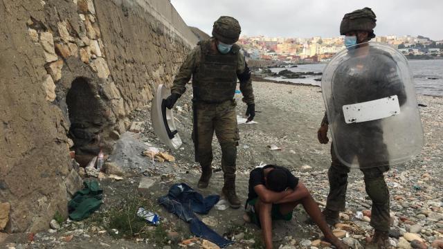 Dos militares españoles atienden a un joven marroquí recién llegado a Ceuta.