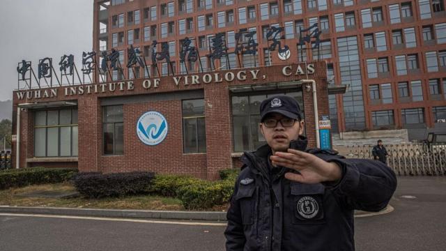 Un policía intenta evitar fotografías del Instituto de Virología de Wuhan durante la visita de la comitiva de la OMS.