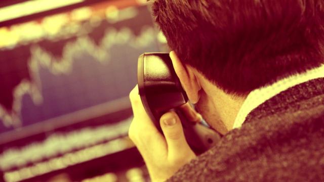 Un bróker consulta pantallas de cotización mientras atiende al teléfono.