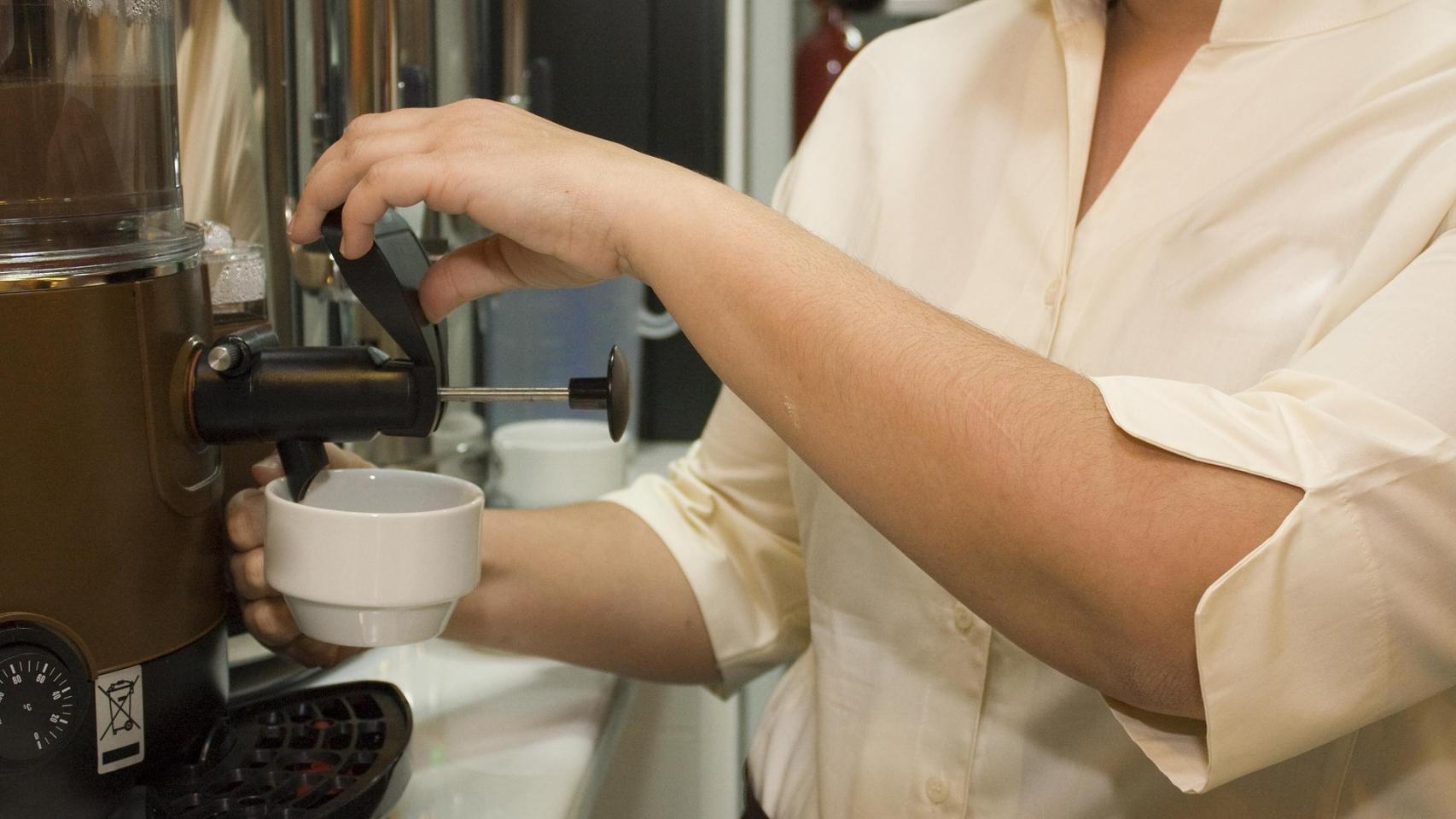 El empleado de un bar sirviendo un café.