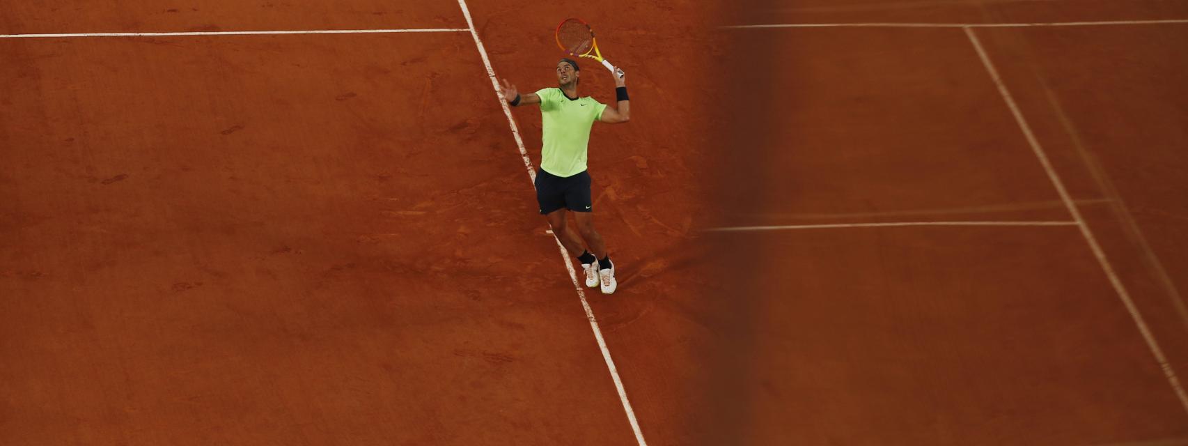 Nadal mientras saca de fondo en la tierra batida de Roland Garros