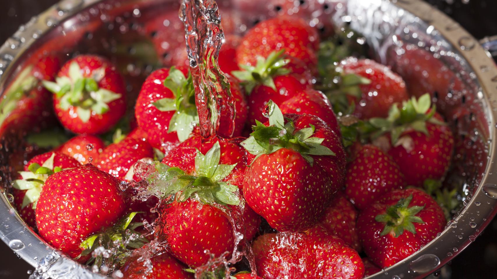Un cuenco de fresas bajo un chorro de agua.