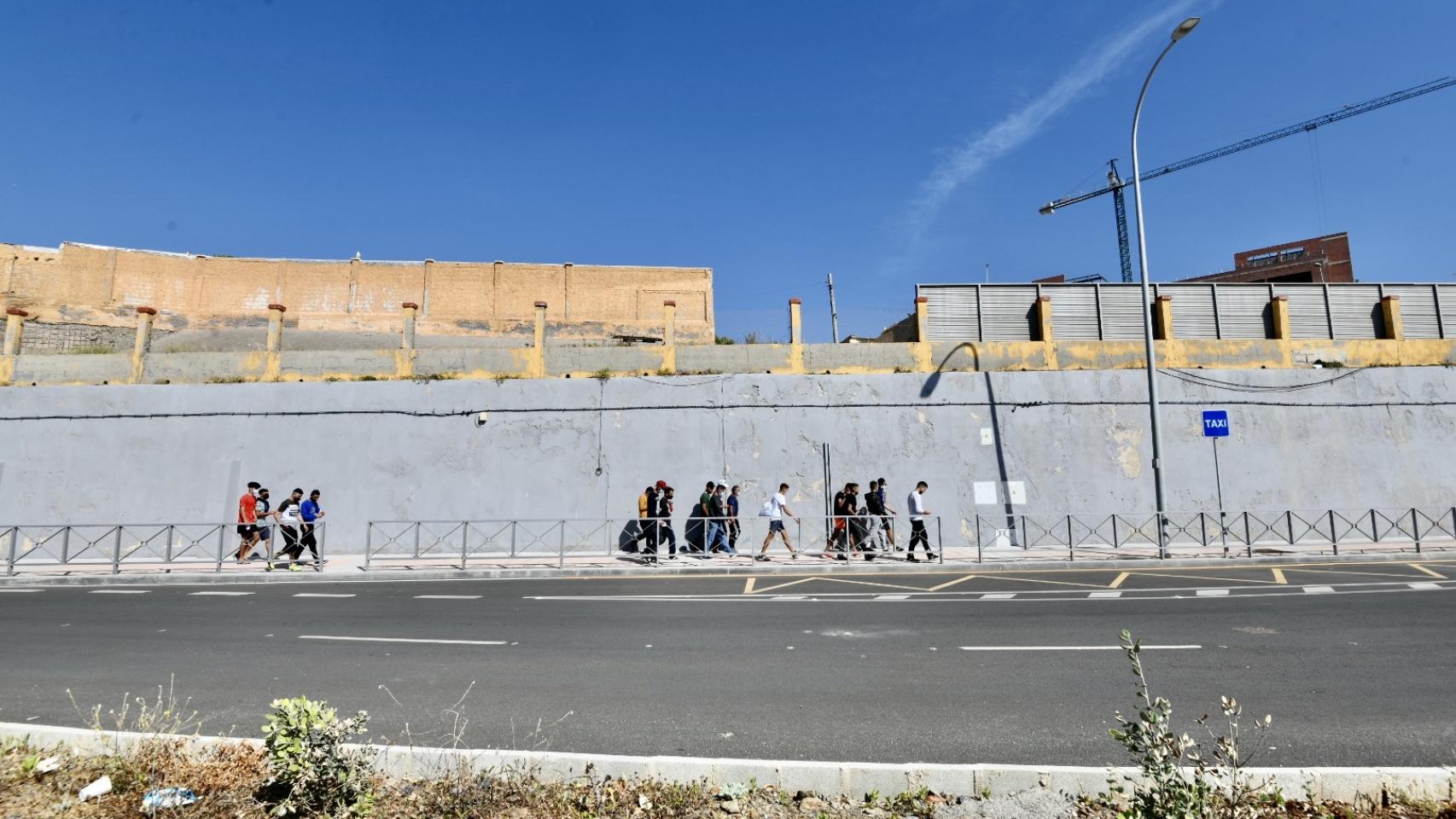 Varios migrantes procedentes de Marruecos hacen cola en las puertas de la frontera de Ceuta.