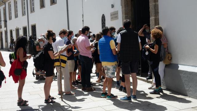Peregrinos con mascarillas esperando su turno para entrar en el albergue.