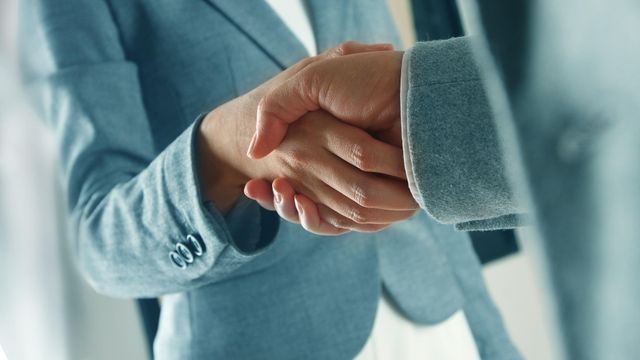 Una mujer y un hombre ejecutivos se dan la mano.