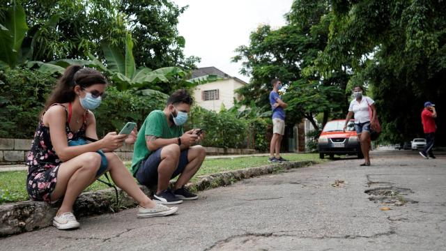 La estudiante Daniela Reyes, junto a su novio, buscando conexión a Internet en un parque de La Habana.