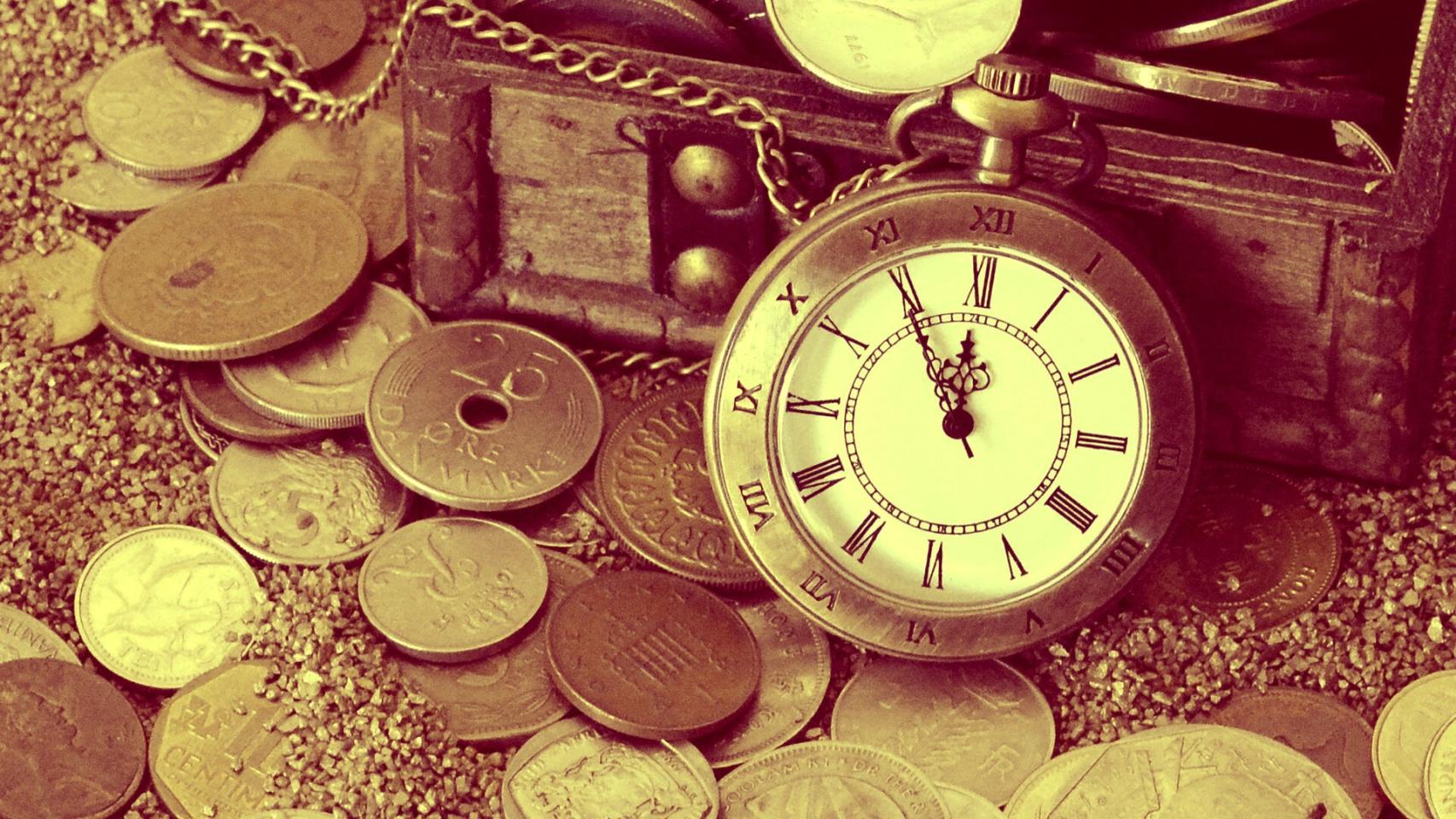 Un reloj junto a monedas de distintas denominaciones.