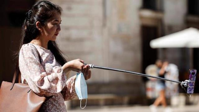 Una turista se hace una fotografía con el teléfono móvil este sábado en el centro de Valencia, durante el fin de semana en el que finaliza julio y da comienzo agosto, muchos empiezan sus vacaciones de verano y otros apuran sus últimos días