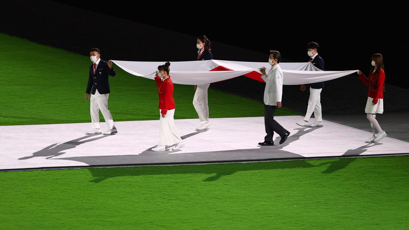 La bandera de Japón portada por los voluntarios de Tokio 2020.