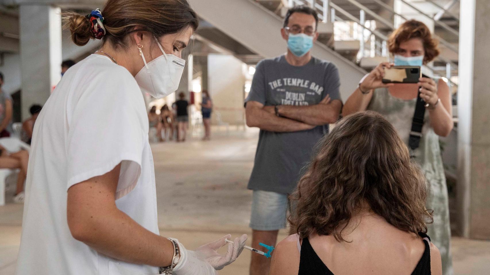 Una enfermera administra la vacuna moderna a una joven.