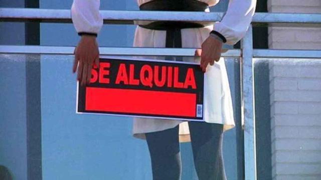 Un propietario coloca un cartel de alquiler.