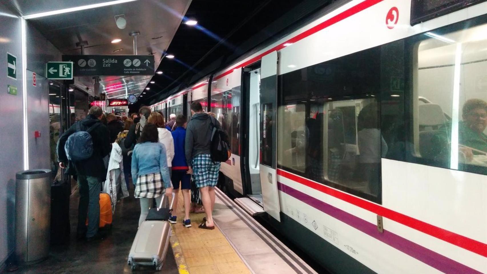 Imagen de varios pasajeros junto a un tren de Cercanías, en Málaga.