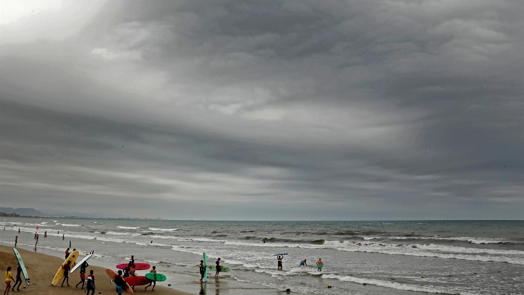 Un grupo de jóvenes entran en el mar con sus tablas de surf en la playa de la Malvarrosa de Valencia