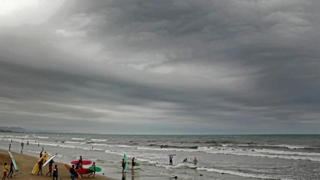 Un grupo de jóvenes entran en el mar con sus tablas de surf en la playa de la Malvarrosa de Valencia