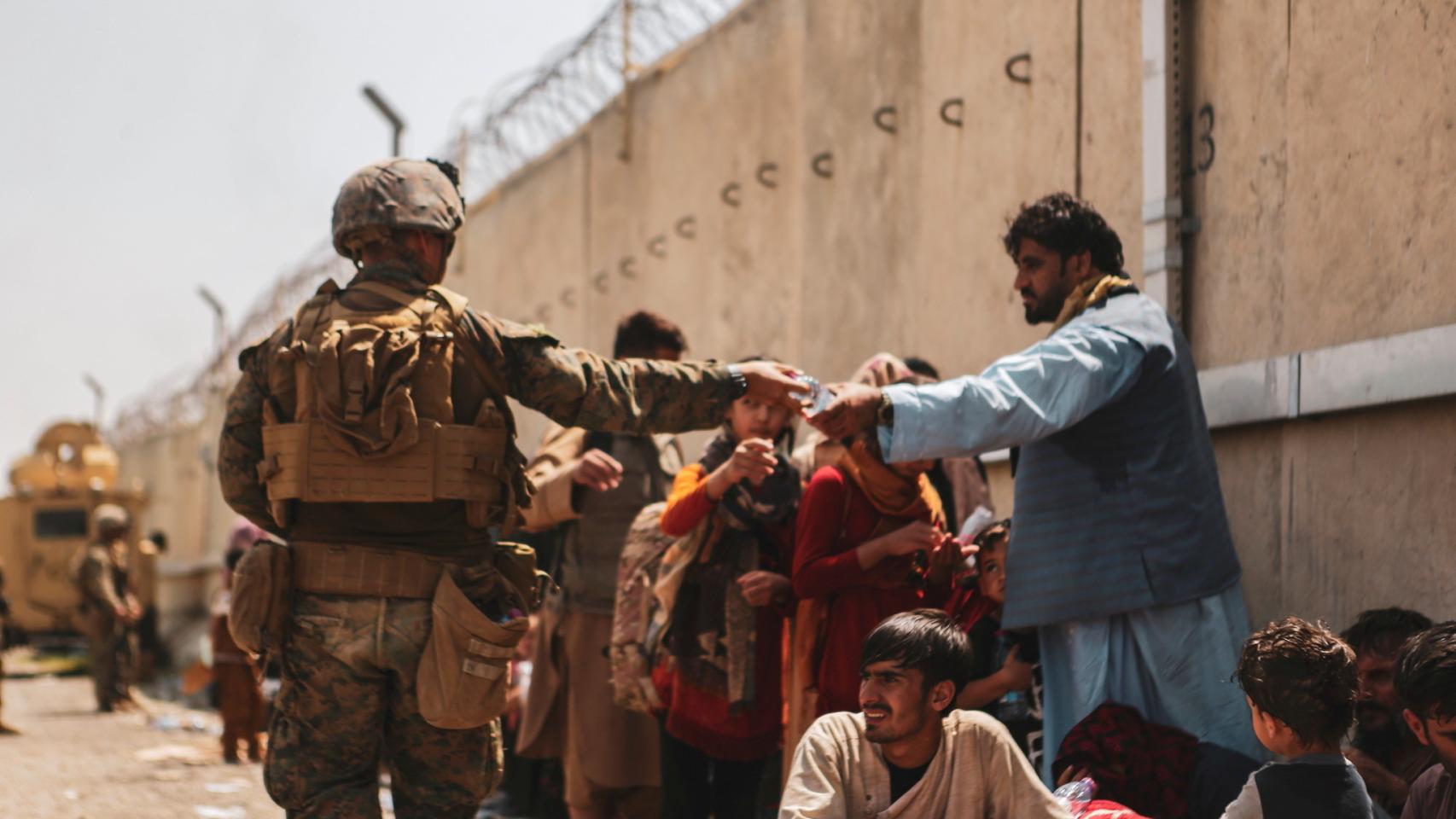 Un marine ofrece botellas de agua a los evacuados en Kabul, en el aeropuerto Hamid Karzai.