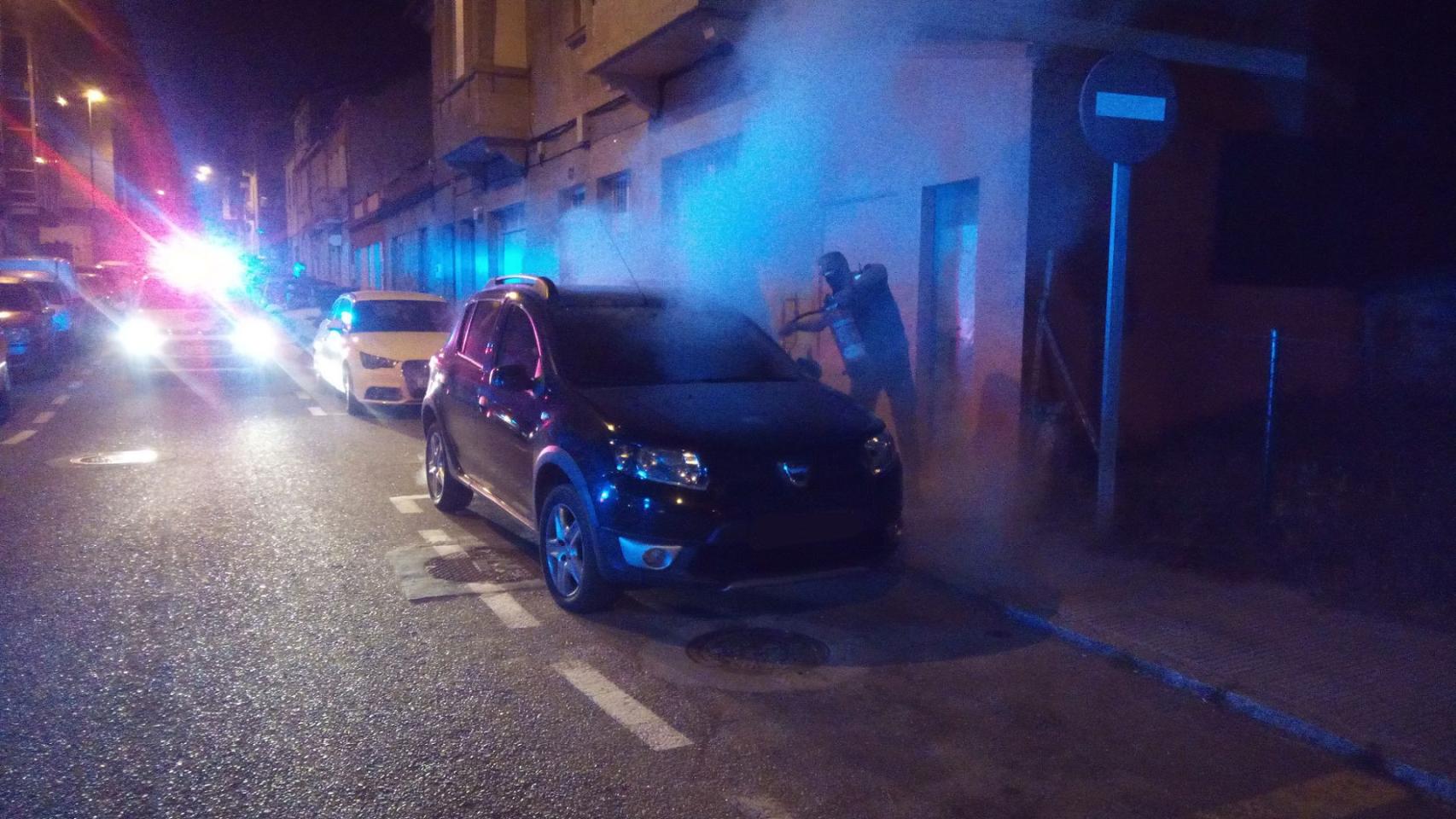 Un agente apaga el fuego de uno de los vehículos.