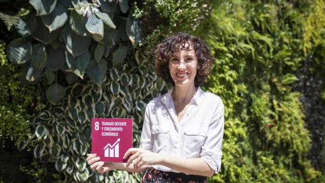Concepción Galdón posa con el cartel del ODS 8 sobre trabajo decente y crecimiento económico.