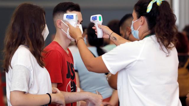 Una sanitaria toma la temperatura a dos jóvenes en Alicante.