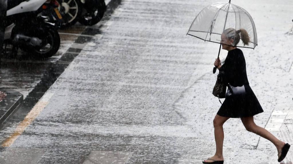 Una mujer sostiene un paraguas mientras llueve.