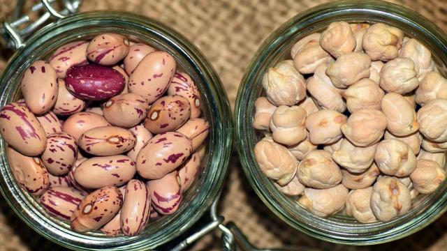 Dos recipientes de vidrio con garbanzos y alubias en su interior.