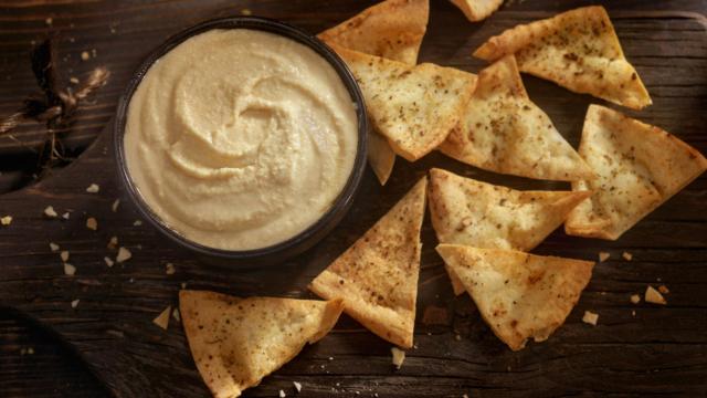 Un cuenco con hummus con chips para mojar.