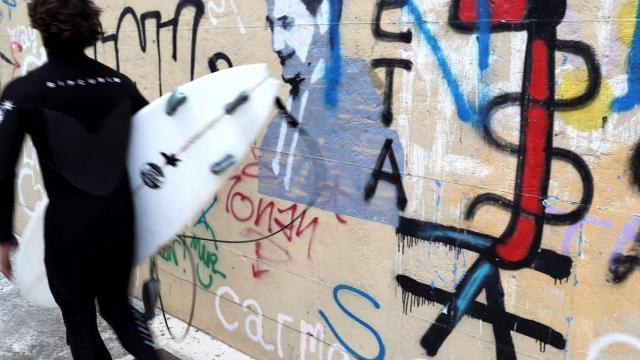 Un surfista frente a una pintada a favor de ETA en las calles de San Sebastián.