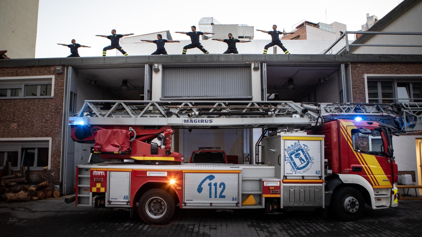 Bomberos instruidos por David practican yoga en la azotea del Parque número 2 de Madrid.