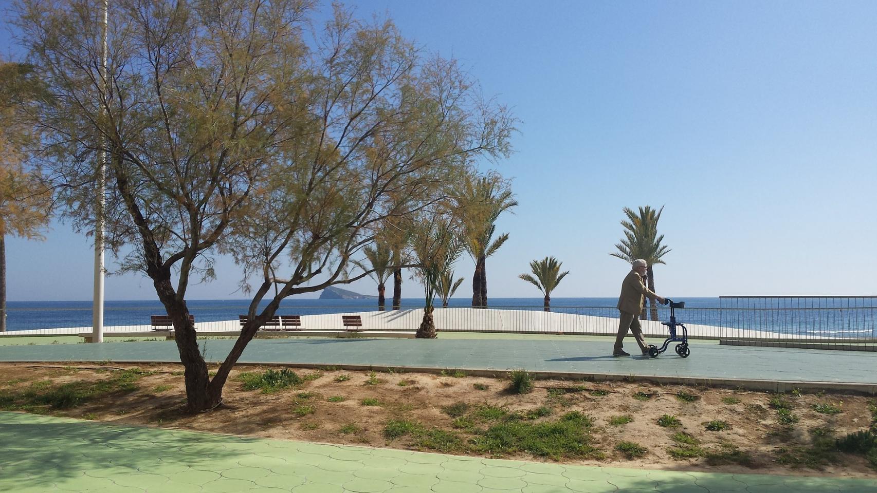 Una persona mayor pasea por el litoral de Benidorm.