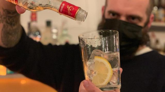 Sergio Ramírez, camarero en Madrid, sostiene una botella de alcohol vacía .