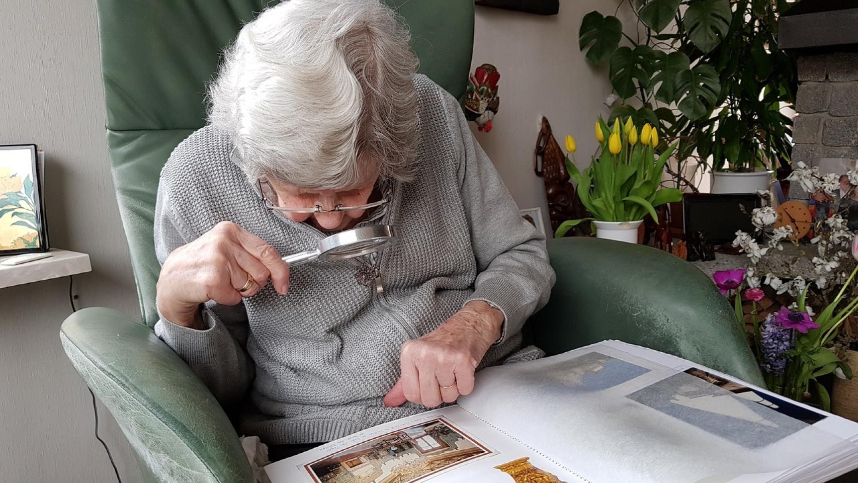 Una anciana mirando por una lupa.