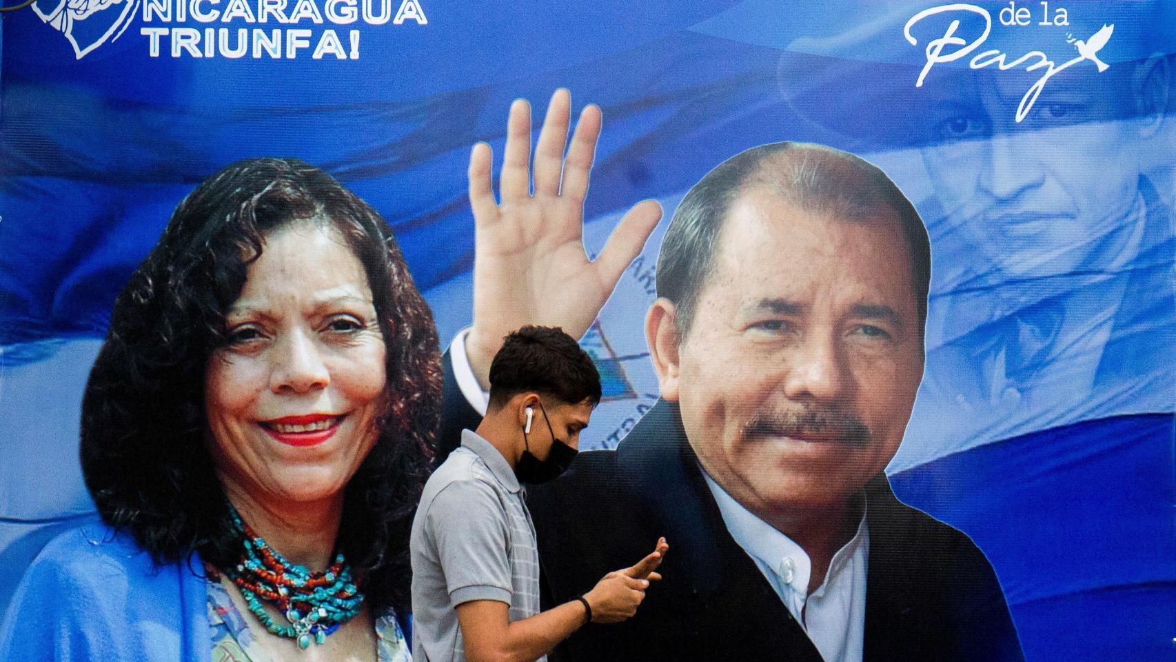Un hombre delante de un cartel electoral de Daniel Ortega, y su mujer, la vicepresidenta, Rosario Murillo.