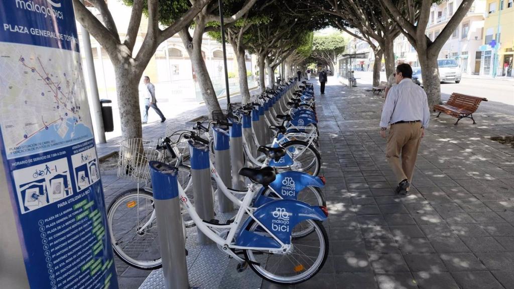 Una persona pasa junto a una de las estaciones del sistema de bicis de alquiler de Málaga, que deja de funcionar.