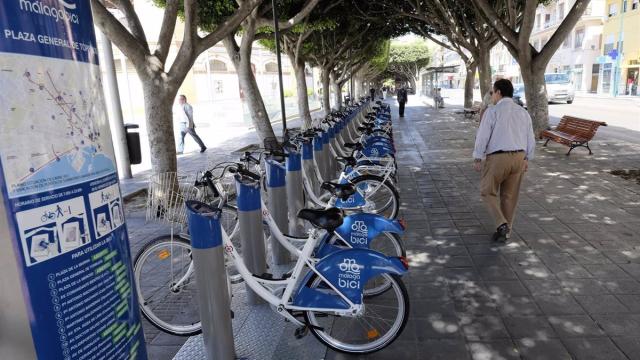Una persona pasa junto a una de las estaciones del sistema de bicis de alquiler de Málaga, que deja de funcionar.