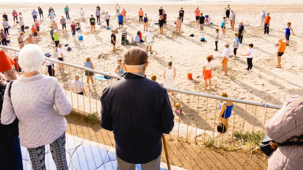 Personas de diferentes edades hacen gimnasia en una playa de Benidorm.