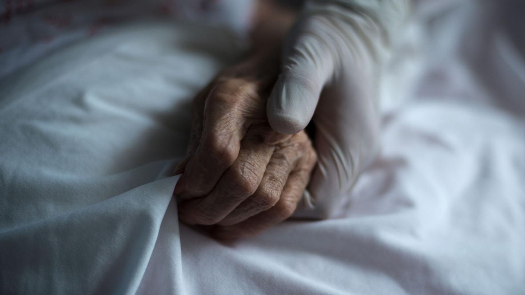 Un sanitario da la mano a una anciana, en imagen de archivo.