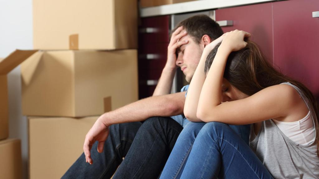 Una pareja se lamenta junto a unas cajas de mudanza.